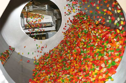 Creatine gummies being processed in a large industrial mixer during manufacturing.