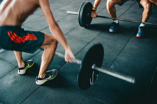 Two people engaged in a workout, lifting barbells to enhance their fitness routine in a gym setting.