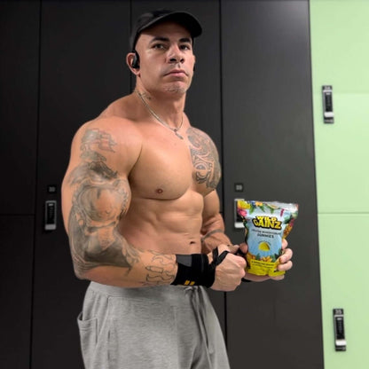 Bodybuilder holding Creatine Monohydrate Gummies pack in a gym locker room.